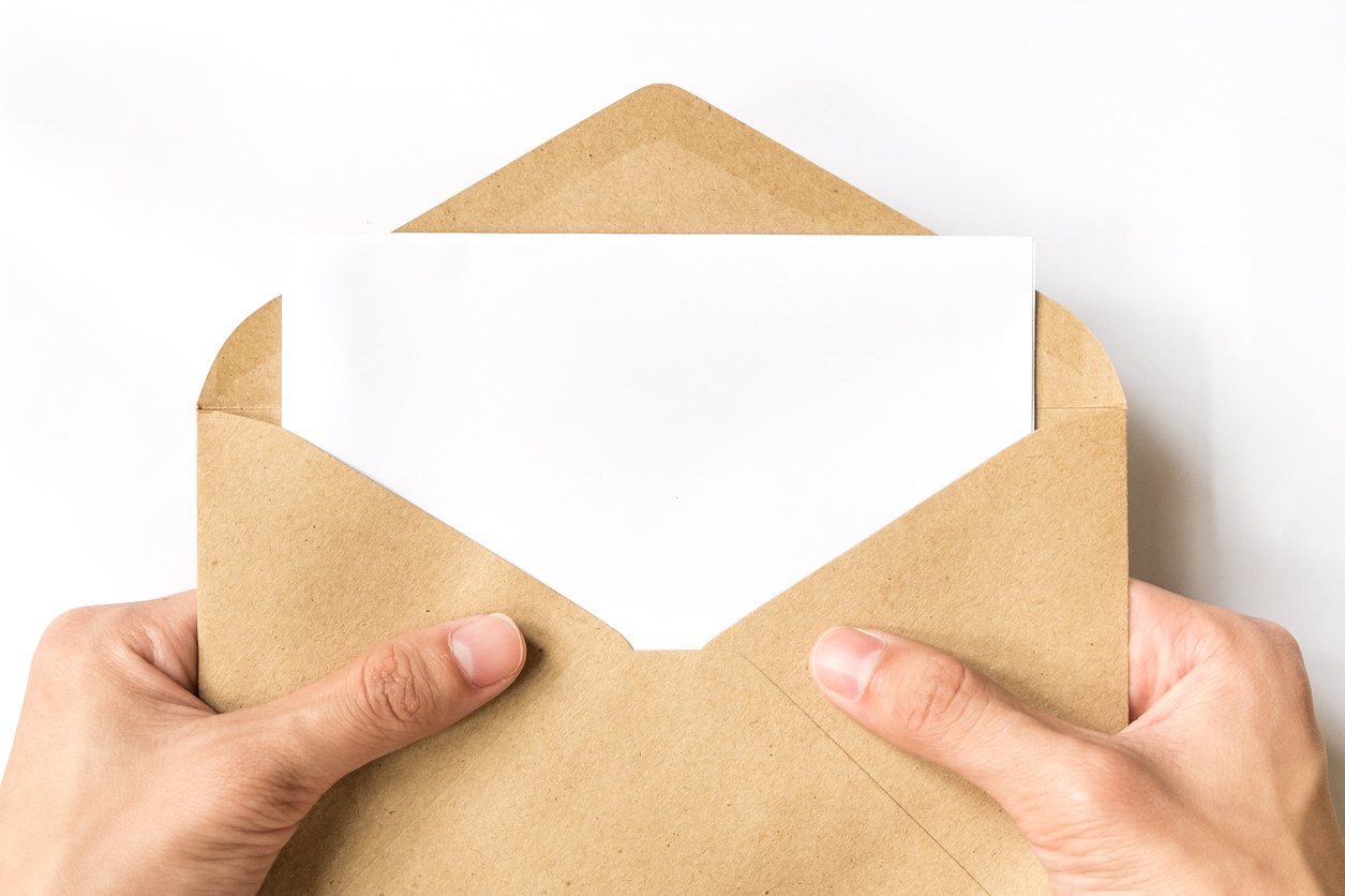 Hands opening a kraft envelope